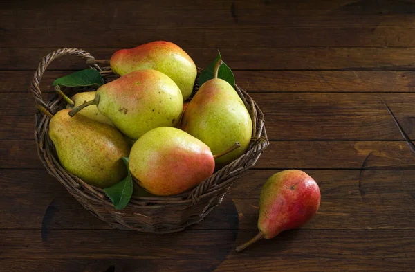 Eski ahşap bir masada sepetteki olgun sulu armutlar ve metin için fotokopi alanı. Yakın plan. Alçak tuş.