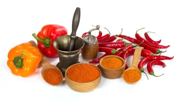 Paprika and chili powder ground in a wooden bowl and spoon on wh — Stock Photo, Image