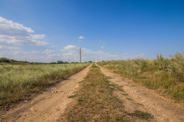 Tarlalardan geçen köy yolu. Güç hatları uzaklıktan görülebilir.