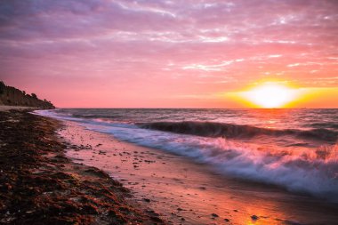 Bulutlu bir sabahta denizde güzel bir gün doğumu. Gemiler ufukta gün doğumunun arka planında görülebilir. Kumlu sahil şeridini bırakıyorum. Karadeniz. Sanzhiika. Ukrayna