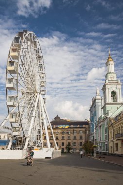 Ukrayna. KYIV - 24 Ekim 2020. Modern dönme dolabın yanındaki eski çan kulesinin manzarası, Sözleşme Meydanı. Güzel sonbahar mavi gökyüzü sirrus bulutlarıyla