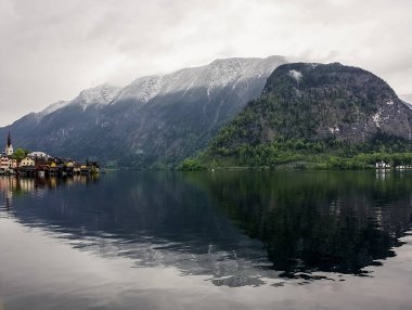 Attersee 'nin göl kenarında sakin bulutlu bir gün ve yazın sonlarında arka planda dağlar. Attersee Gölü Avusturya Salzkammergut 'unda