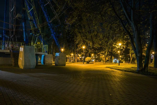 夜の公園の観覧車 秋の夜に公園でベンチ 夜になると提灯のついた公園道のイルミネーション — ストック写真