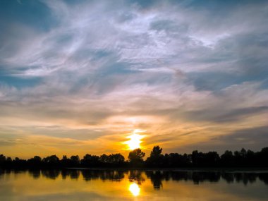 Nehirde güzel bir gün batımı ve bulutlu bir gökyüzü