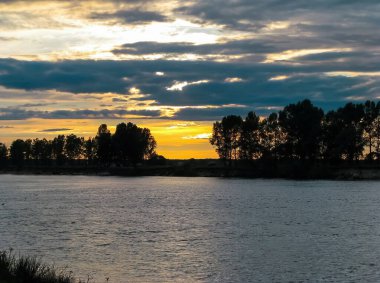 Nehirde güzel bir gün batımı ve bulutlu bir gökyüzü