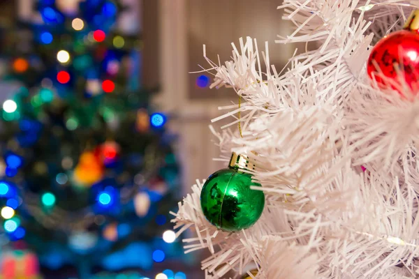 Green christmas ball on a white branch against the background of a christmas tree. New Year concept.