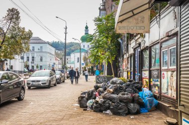 Ukrayna. Kyiv - 11 Kasım 2020. Şehrin tarihi merkezinde kaldırımda çöp torbaları - Podol ve arka planda Mykola Prytyska Kilisesi.