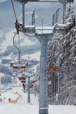 Ukrayna. Bukovel - 02 Şubat 2021. Kayakçılarla ve noel ağaçlarıyla kayak kaldırma. Asansörün bir kısmı dumanlı, kış bulutlu bir gün..