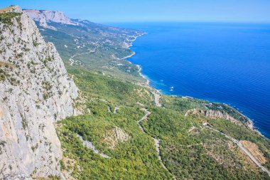 Akdeniz manzarası. Kırım Yarımadası 'nın güney kıyısındaki Karadeniz kıyısındaki orman kayaları güneşli bir günde. Kayalık dağlardan denize bak.