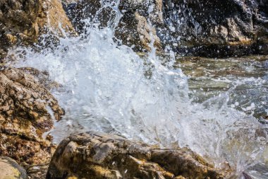 Taşlı bir plajda dalgalar kırılıyor, bir sprey oluşturuyorlar. Kapat.