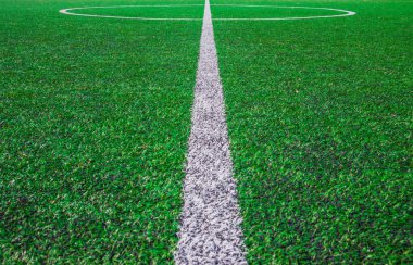 Futbol sahasının ortasında, okulun yanında suni yeşil çimenler ve beyaz çizgiler var. Amatör futbol sahası. Güneşli yaz günü