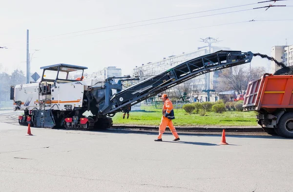 Road construction working. The road milling machine removes old asphalt and loads milled asphalt into the dump truck. Road repair process