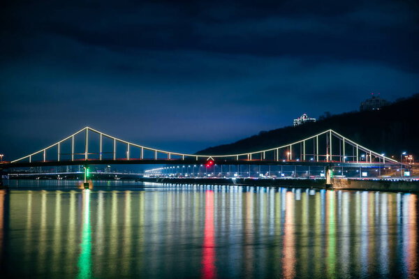 Foot bridge in Kiev at night. Beautiful bridge over the river with LED lighting at night. Ukraine.