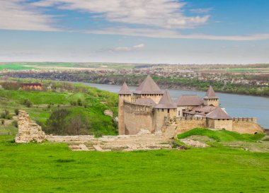 Hotin Kalesi 'nin nehir kenarındaki manzarası. Khotyn Kalesi - Sarı sonbahar tepelerindeki ortaçağ kalesi. Ukrayna, Doğu Avrupa. Orta Çağ 'ın mimarisi..