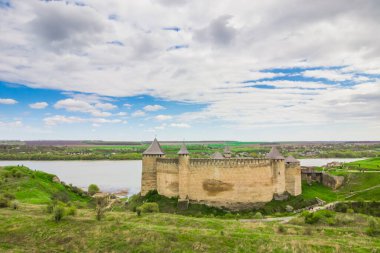 Hotin Kalesi 'nin nehir kenarındaki manzarası. Khotyn Kalesi - Sarı sonbahar tepelerindeki ortaçağ kalesi. Ukrayna, Doğu Avrupa. Orta Çağ 'ın mimarisi..