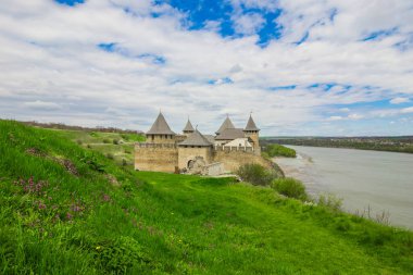 Hotin Kalesi 'nin nehir kenarındaki manzarası. Khotyn Kalesi - Sarı sonbahar tepelerindeki ortaçağ kalesi. Ukrayna, Doğu Avrupa. Orta Çağ 'ın mimarisi..