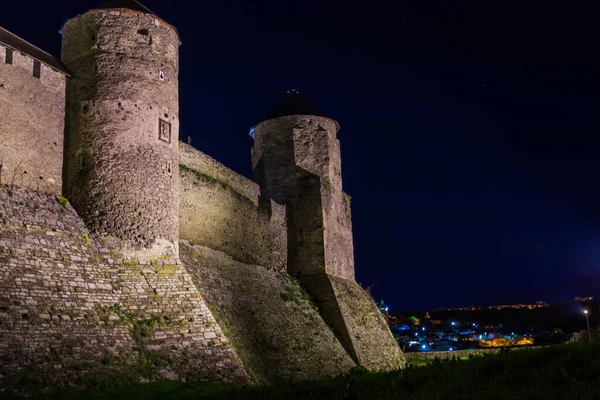 View of the towers and walls of the Kamianets-Podilskyi Castle in the night. Stone bastion of an ancient castle. Beautiful stone castle on the hill at night. Ukraine