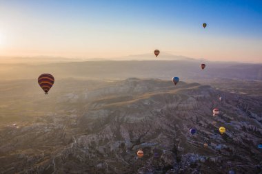 Kapadokya, Türkiye 'de vadi üzerinde uçan sıcak hava balonları. Goreme Balon Festivali. Güzel sıcak hava balonları gün doğumunda havalanır.