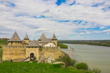 Hotin Kalesi 'nin nehir kenarındaki manzarası. Khotyn Kalesi - Sarı sonbahar tepelerindeki ortaçağ kalesi. Ukrayna, Doğu Avrupa. Orta Çağ 'ın mimarisi..