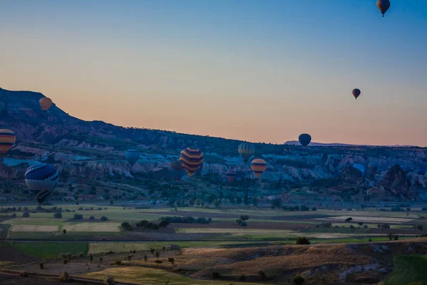 Hot air balloons flying over the valley at Cappadocia, Turkey. Goreme Balloon Festival. Beautiful hot air balloons take off at sunrise. Hot air balloons in the blue sky