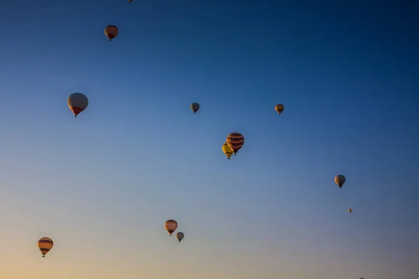 Hot air balloons flying over the valley at Cappadocia, Turkey. Goreme Balloon Festival. Beautiful hot air balloons take off at sunrise. Hot air balloons in the blue sky