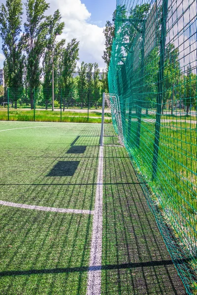 Goal on a football field with artificial green grass near the school. Amateur football field. Sunny summer day