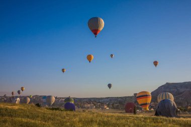 Kapadokya, Türkiye 'de vadi üzerinde uçan sıcak hava balonları. Goreme Balon Festivali. Güzel sıcak hava balonları gün doğumunda havalanır. Mavi gökyüzünde sıcak hava balonları