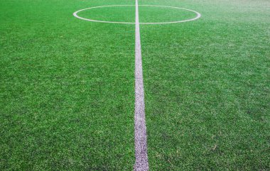 Futbol sahasının ortasında, okulun yanında suni yeşil çimenler ve beyaz çizgiler var. Amatör futbol sahası. Güneşli yaz günü