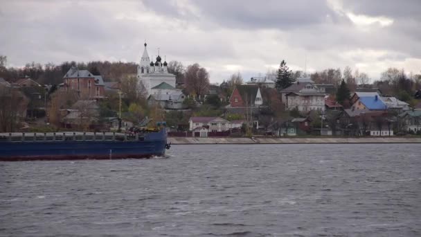 Kostroma, Russia - 20 жовтня 2020: Сухий вантажний корабель "Otradny" проходить вздовж річки Волга навпроти церкви в Костромі в осінній хмарний день — стокове відео