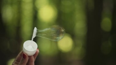 Ormanın arka planında sabun köpükleri var. Çekimler balonun nasıl şiştiğini gösteriyor.