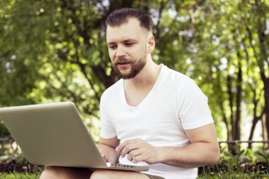 Hipster adam parkta çalışan dizüstü bilgisayar ile