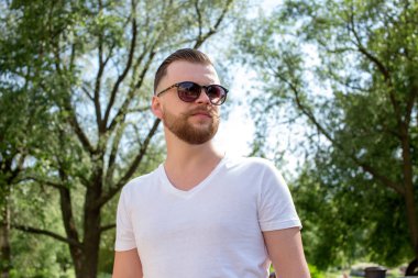 Genç adam bir sakal ve bıyık güneş gözlüğü ve beyaz t-