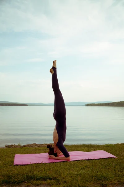 若い女性は山の湖でヨガを練習します。 — ストック写真