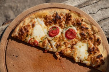 Kırsal ahşap masada sıcak ev yapımı Pepperoni Pizza. Domatesli pizza, peynirli ve fesleğenli..