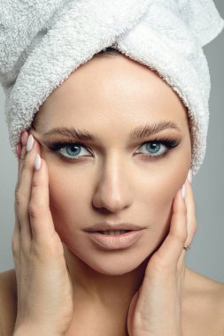 Güzellik tedavisinden sonra saç havlusu giyen kaplıca güzeli kadın. Gri arka planda mükemmel cilde sahip güzel genç bir kadın..