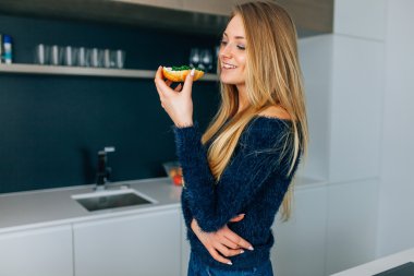 Güzel genç kız mutfakta sandviç yeme. 