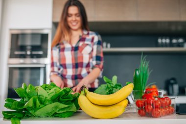Genç kadın bir ekmek kesiyor. İlk planı sebze Tarih ve