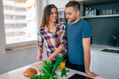 Genç çift akşam yemeği hazırlıyor. Kız kesme besindir. H adamdır