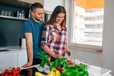 Genç çift akşam yemeği hazırlıyor. Kız kesme besindir. H adamdır