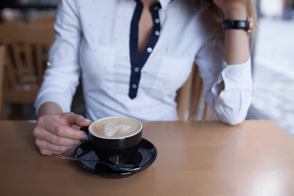 Jong meisje zitten in het cafe met warme koffie. Close-up. — Stockfoto