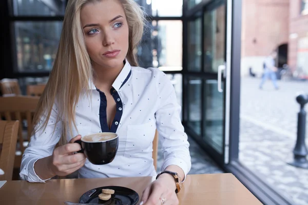 Jovem sentada no café com café quente . — Fotografia de Stock