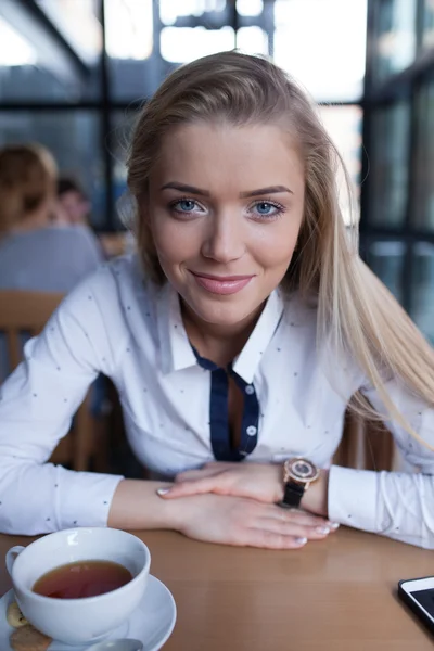 Piękna młoda dziewczyna siedzi w kawiarni. Kawa i telefony — Zdjęcie stockowe