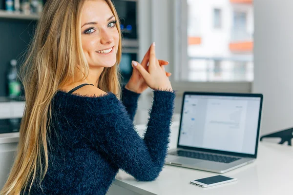 Piękna młoda kobieta siedzi w kuchni z laptopa. Wznios — Zdjęcie stockowe