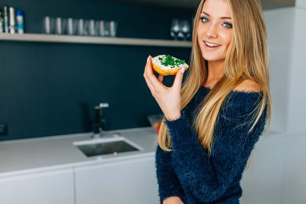 Menina bonita comendo sanduíches na cozinha . — Fotografia de Stock