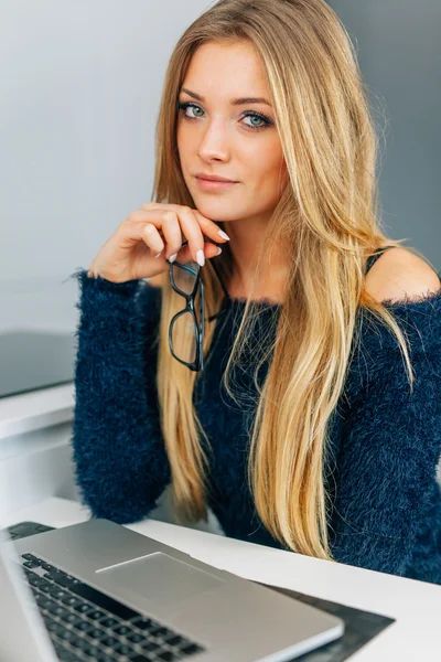 Giovane ragazza seduta in cucina con computer portatile. Lei sta tenendo ey — Foto Stock