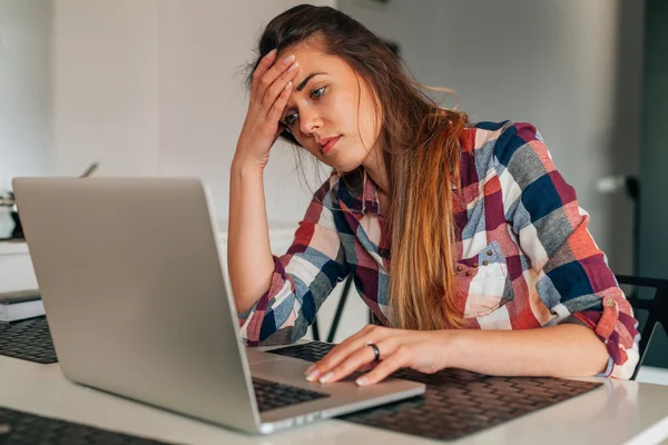 Chica triste sentado i la cocina y el uso de la computadora portátil . — Foto de Stock