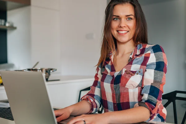 Mutlu genç kadın mutfakta dizüstü bilgisayar kullanarak. — Stok fotoğraf