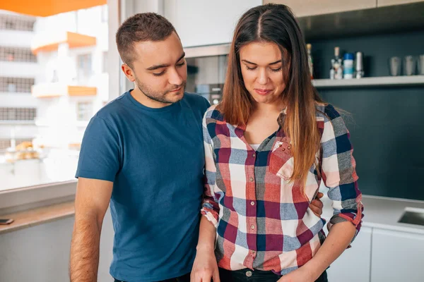 Pareja joven parada en el kithcen. Se están abrazando . — Foto de Stock