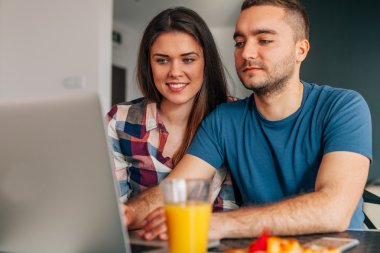 Kithcen içinde oturan ve dizüstü bilgisayar kullanarak genç Çift.