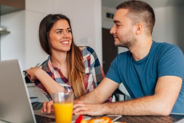 Kithcen içinde oturan ve dizüstü bilgisayar kullanarak genç Çift.